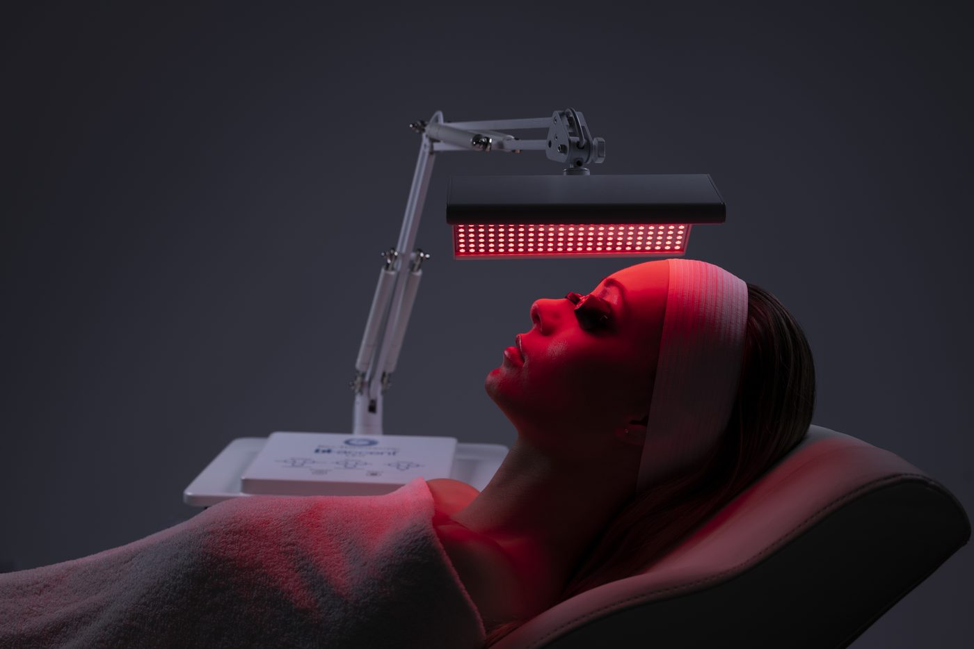 A guest under a red LED light therapy panel