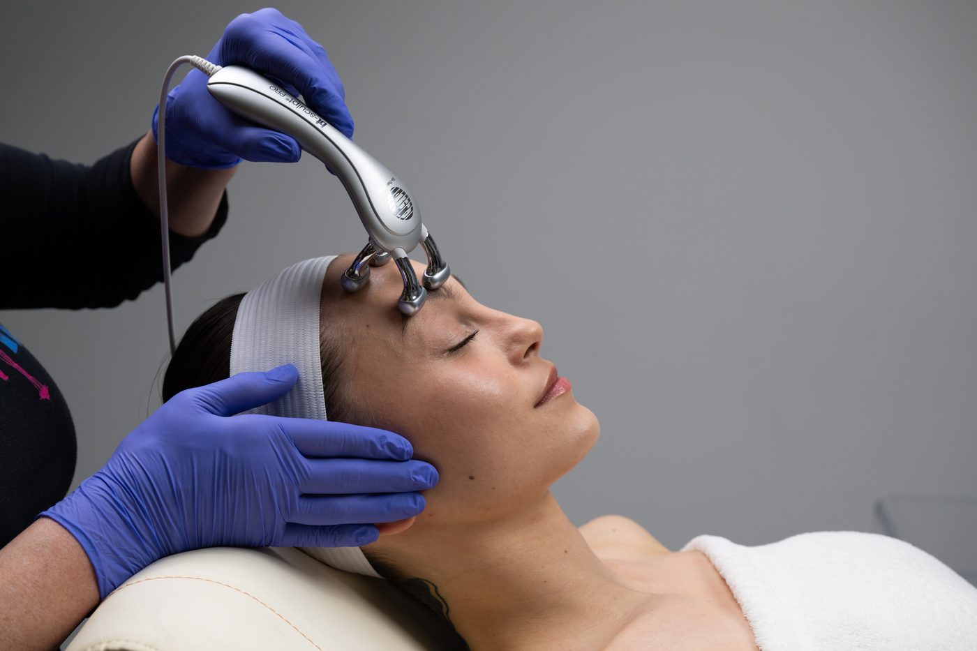 A microcurrent handpiece being worked across a guest's forehead