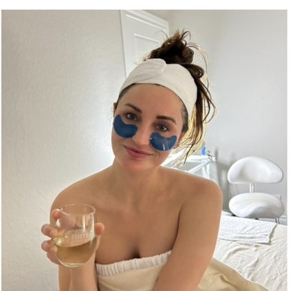 A relaxed guest with eye masks and a glass of wine after her treatment